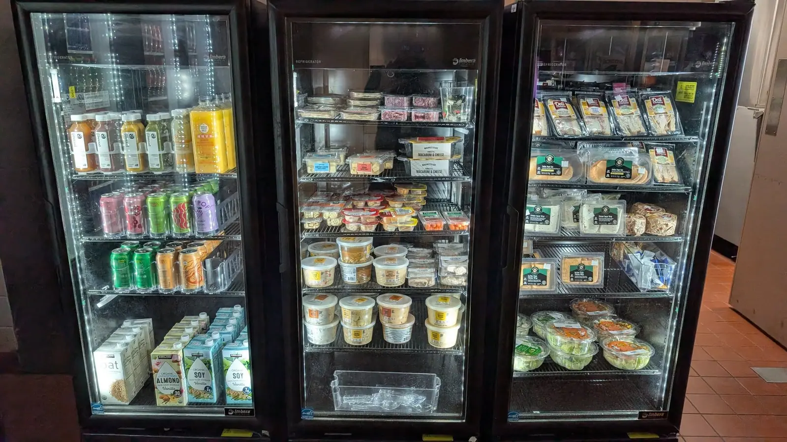 Three glass-door coolers stocked with fresh sandwiches, salads and drinks